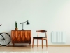 Stylish chair next to retro cabinet and vintage bike in scandinavian minimal interior with mockup on the wall and carpet on the wooden floor, real photo with copy space on the wall